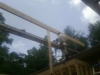 Carpenter setting a ridge beam over a new addition frame in Stockbridge