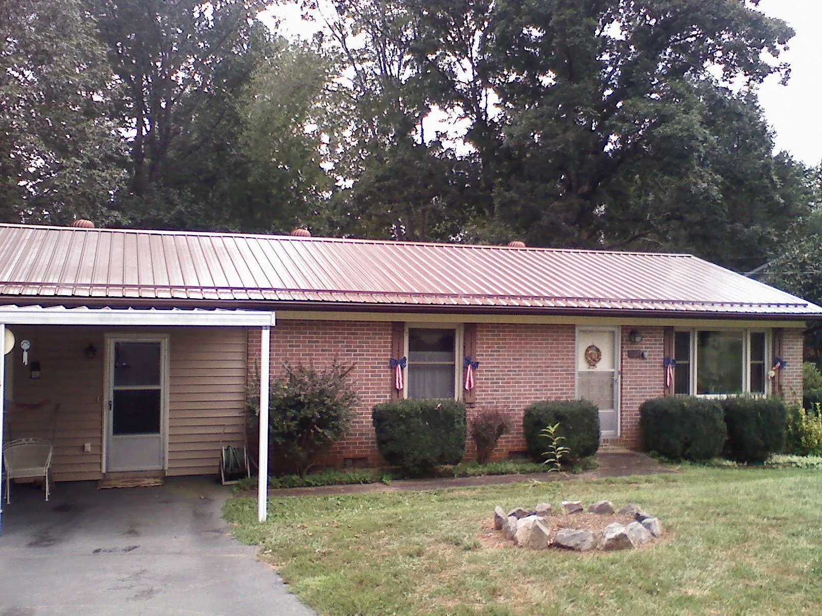 Bronze metal roof and carport on a brick ranch home — Roof Repair work by our crew in Stockbridge