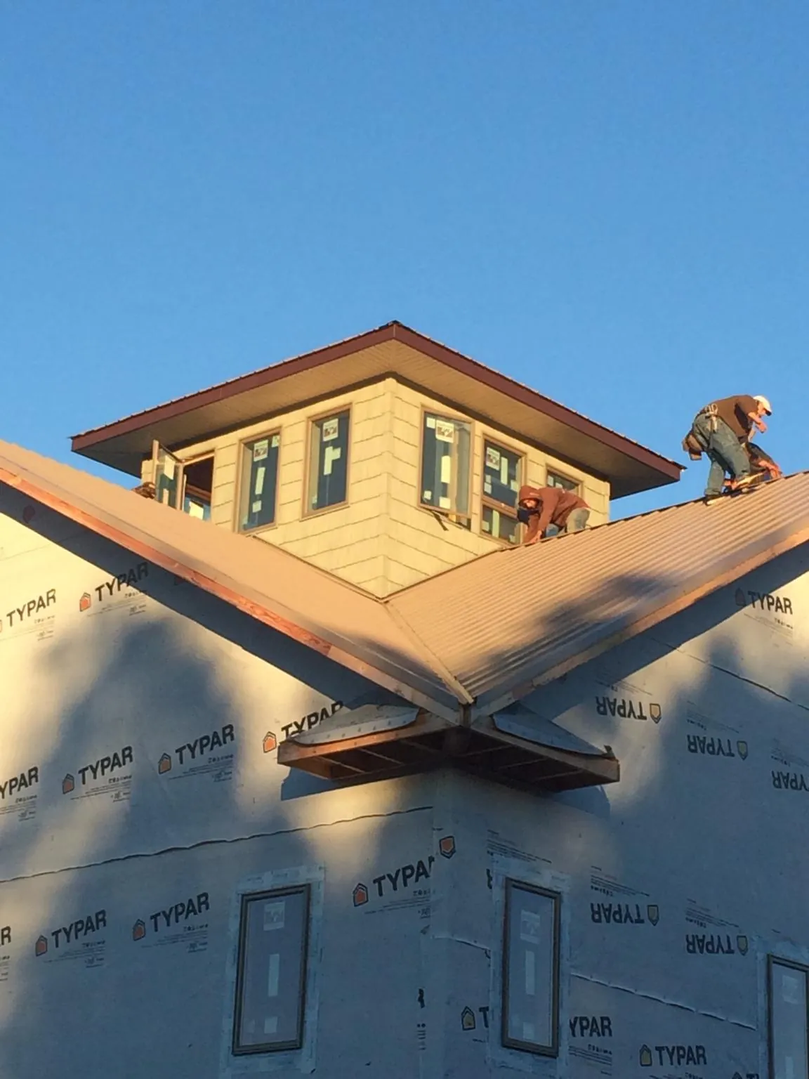 Roofers working around a rooftop cupola on a new metal roof at sunset — Roof Waterproofing in Stockbridge by Roofing Brothers
